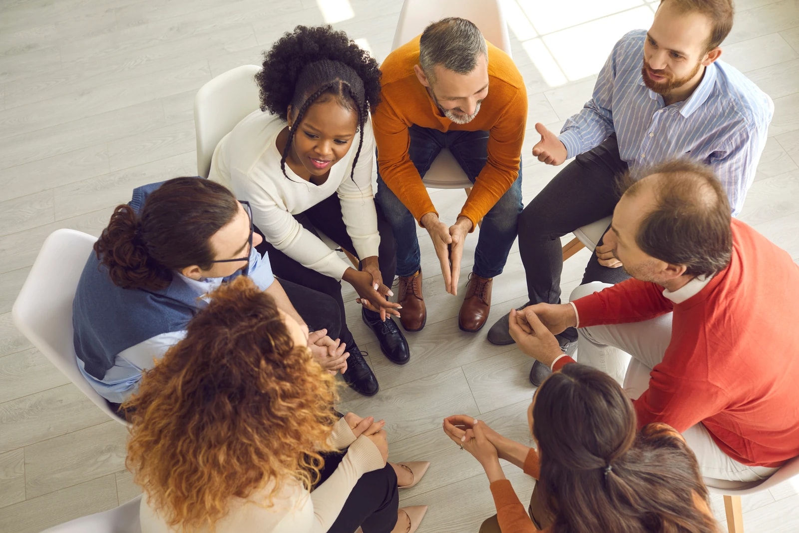 A diverse group seated in a circle in open discussion, viewed from above