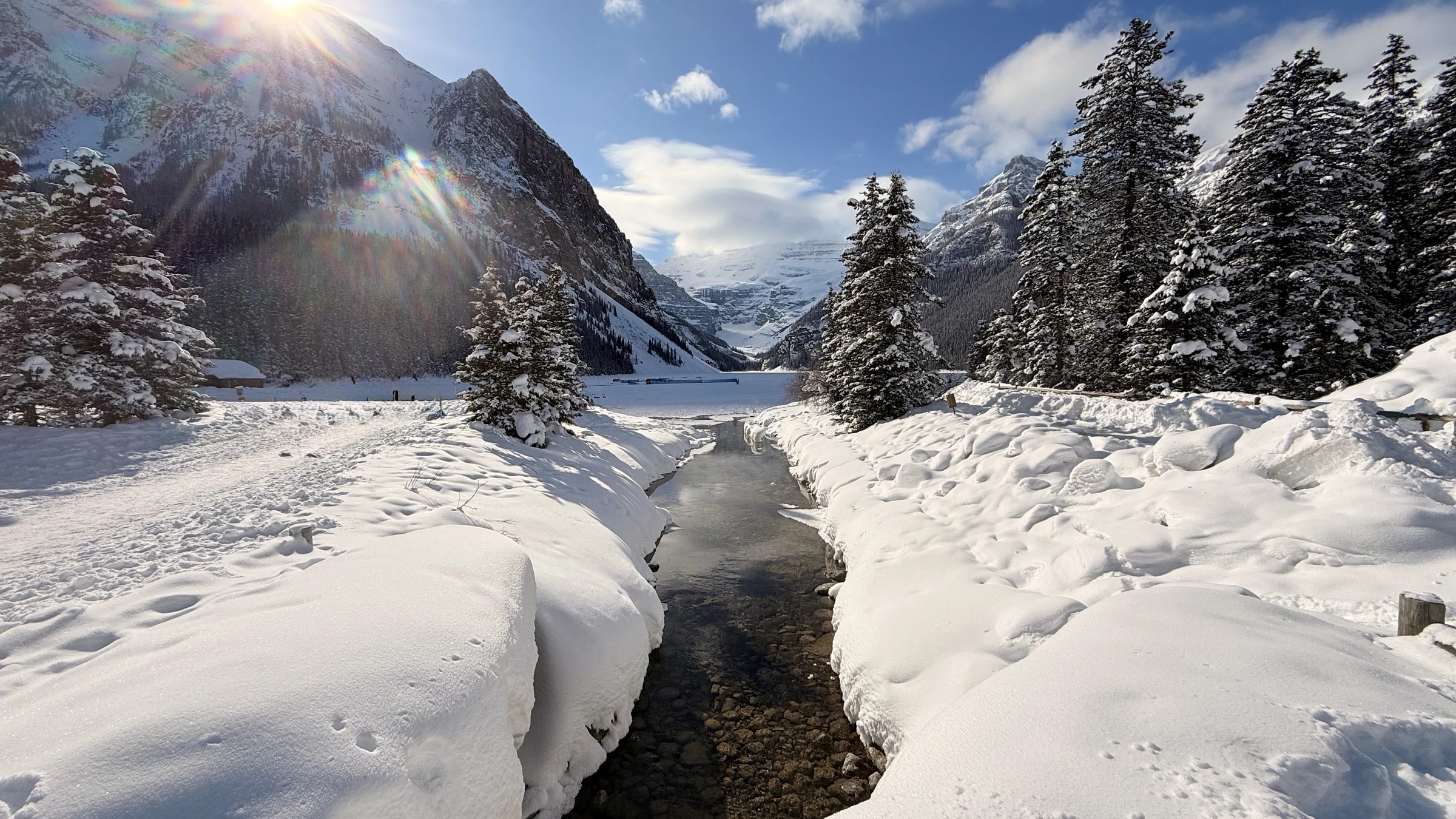 Snow-covered mountains above a small river winding through the valley